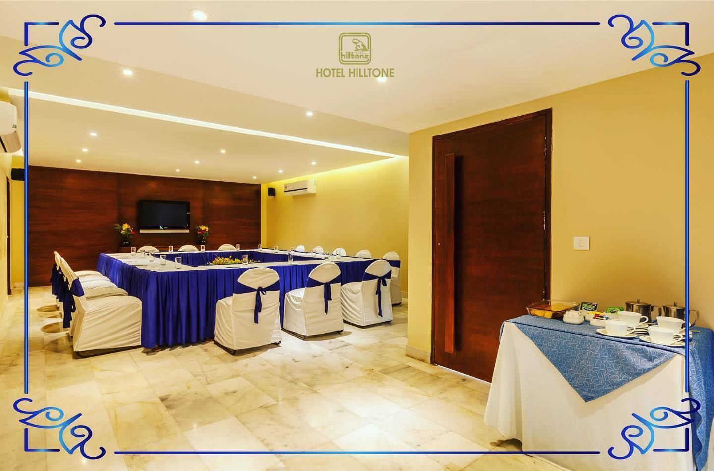 Un salón de conferencias en el Hotel Hilltone con una larga mesa, sillas y una mesa pequeña con tazas y una tetera.