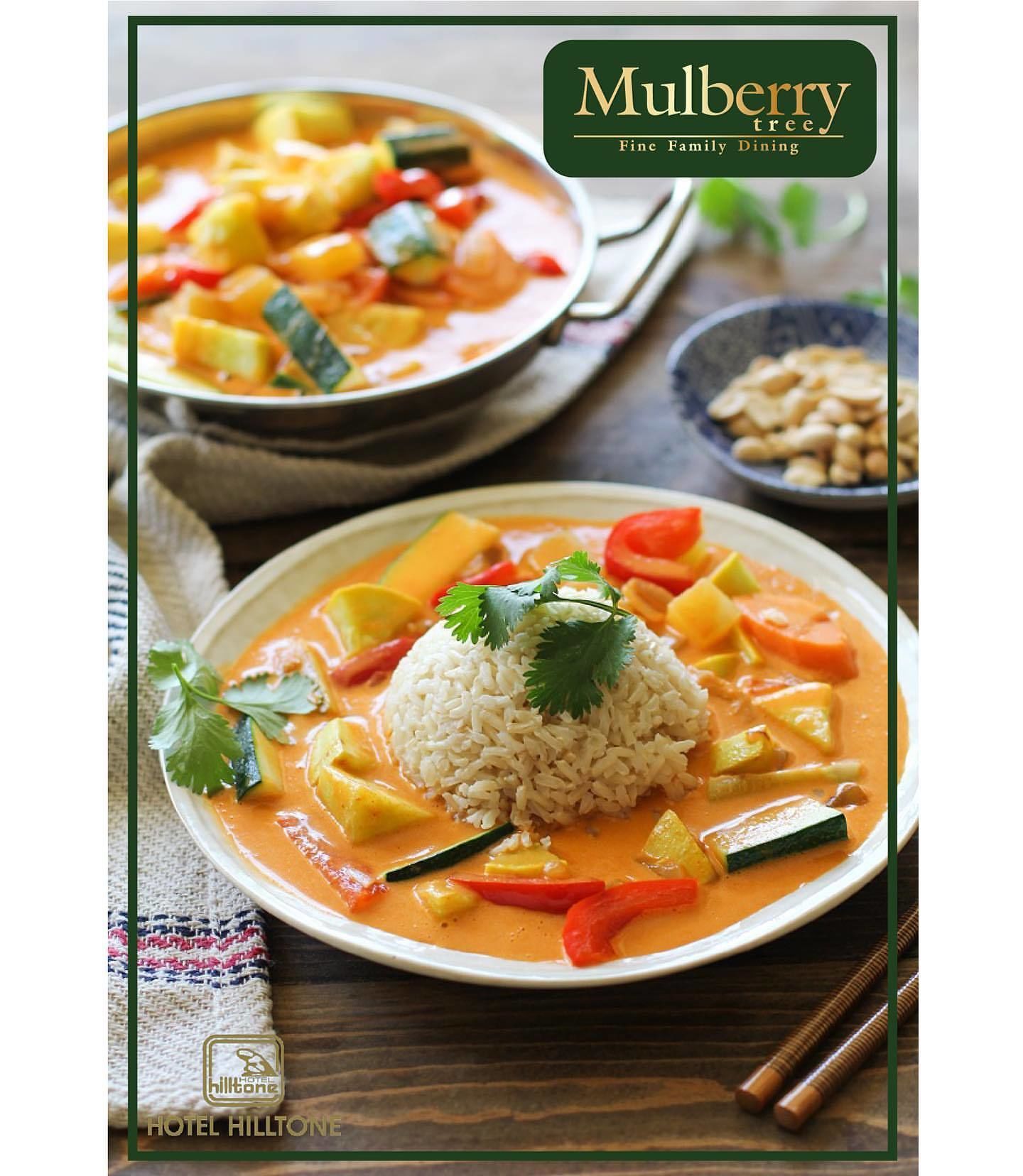 Un tazón de Mulberry tree, restaurante familiar de alta calidad, presenta un cremoso curry de naranja con verduras y arroz, acompañado de maní.