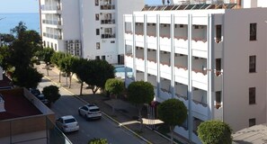 Un edificio a più piani con balconi, un'area di parcheggio e vista mare.
