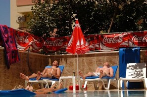 Allasalue, jossa on aurinkotuoleja ja Coca-Cola-mainosbanderolli.