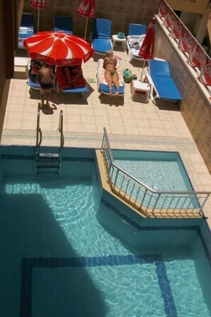 Ein Swimmingpool mit einer Leiter, Liegestühlen und Sonnenschirmen.