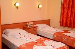 Ein Hotelzimmer mit zwei Betten, einem Holzkopfteil, einem Nachttisch mit Telefon und zwei Wandleuchten.