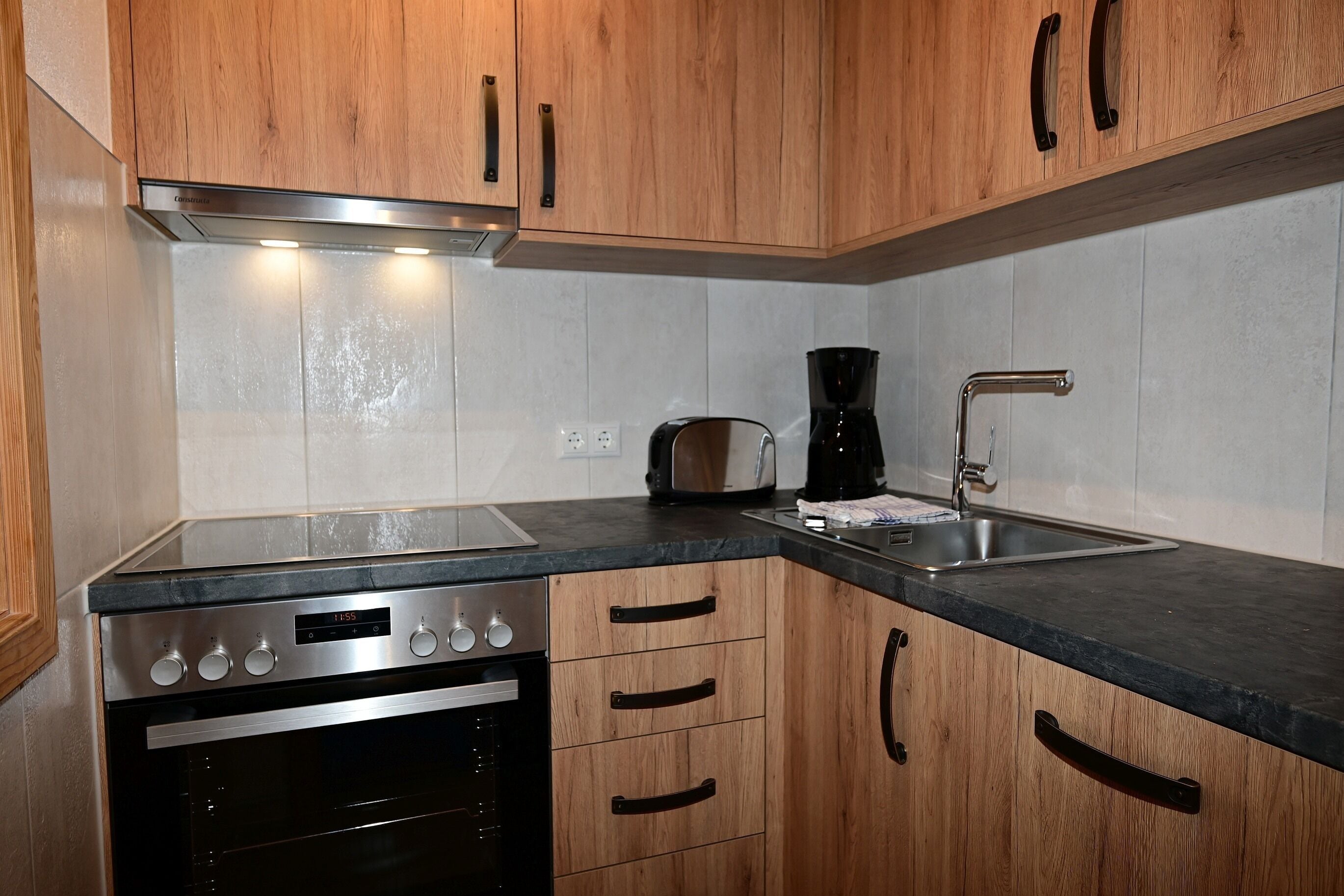 A kitchen with wooden cabinets, a stainless steel oven, a coffee maker, and a sink.