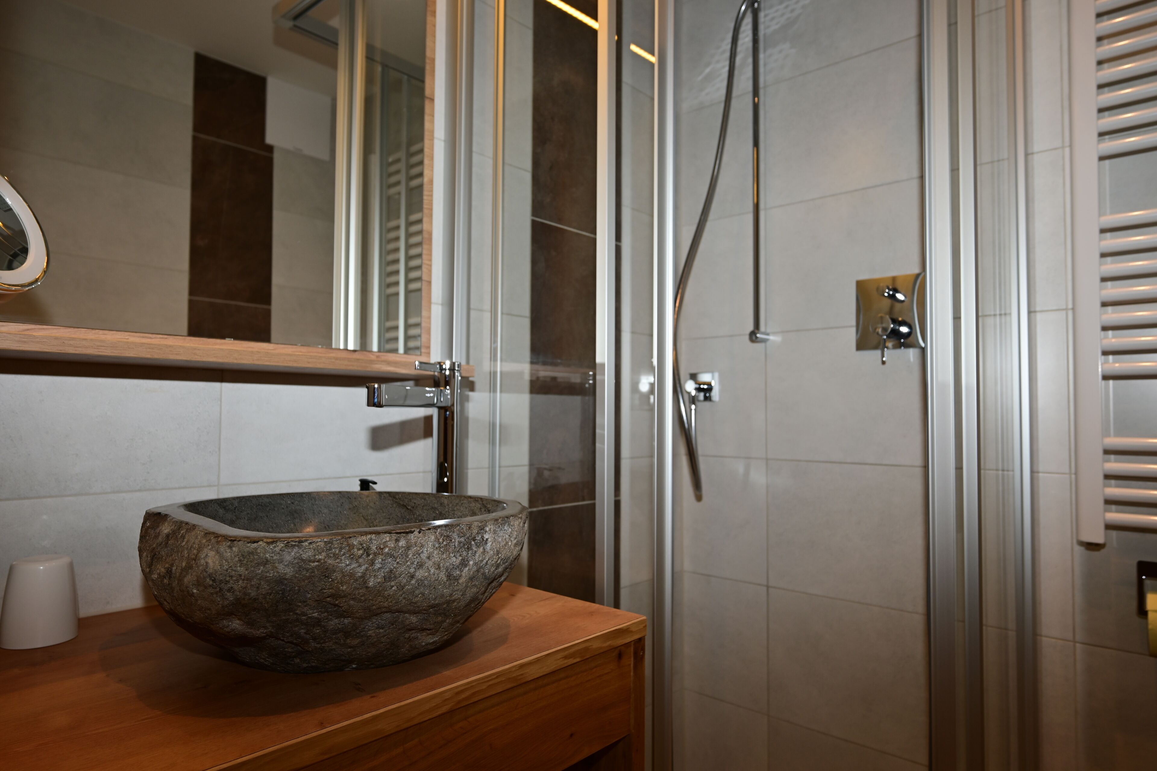 A bathroom with a stone basin sink, a mirror, and a glass-enclosed shower.