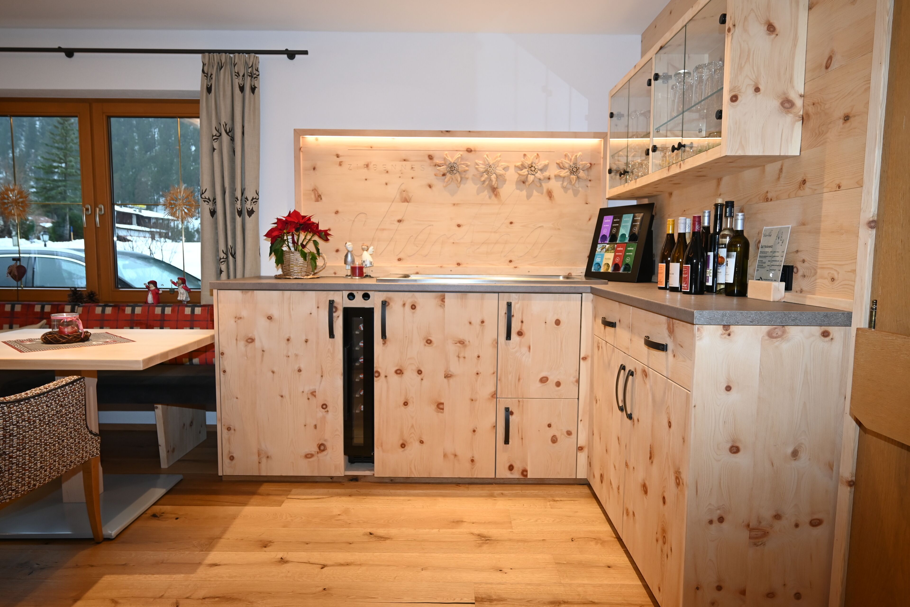 A modern kitchen with wooden cabinetry, a built-in wine rack, and a dining area with a table and chairs.