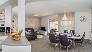 Una sala de estar moderna con comedor, cocina y un amplio ventanal.