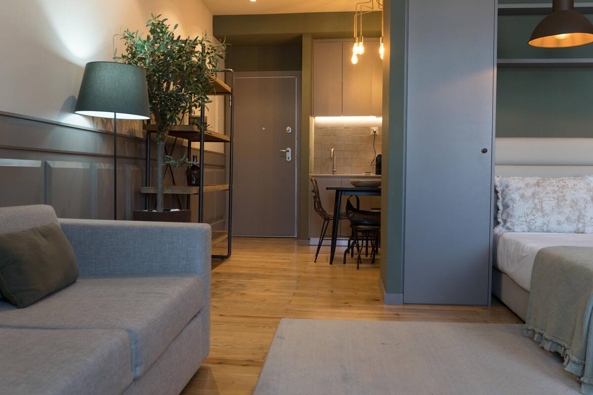 Un espacio habitable compacto con sofá, cama, zona de comedor y kitchenette.