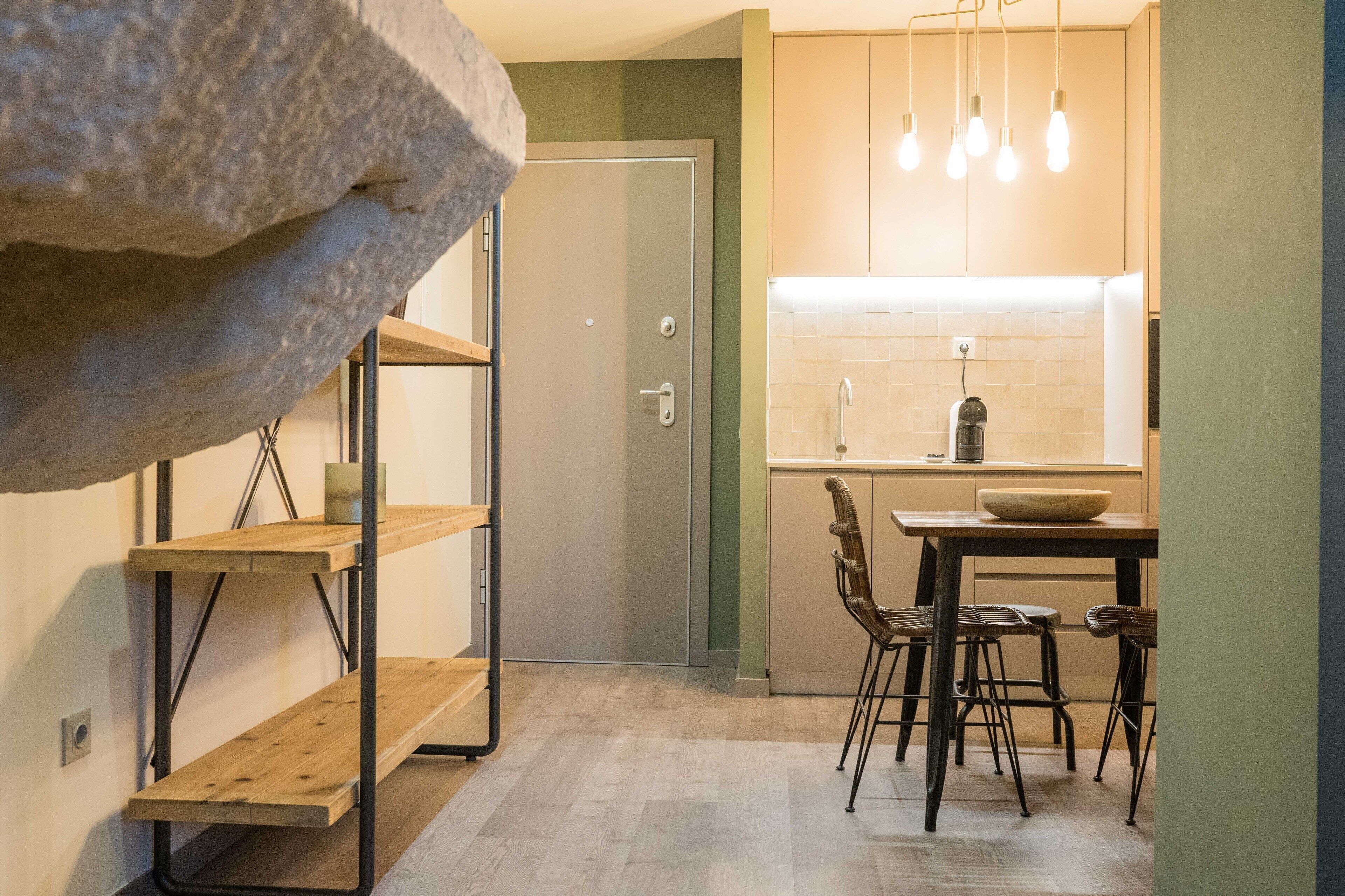 Una cocina compacta con comedor, estantes de madera y detalles de piedra.