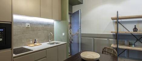 Una cocina moderna con estufa integrada, un lavamanos y una zona de comedor con mesa y sillas de madera.