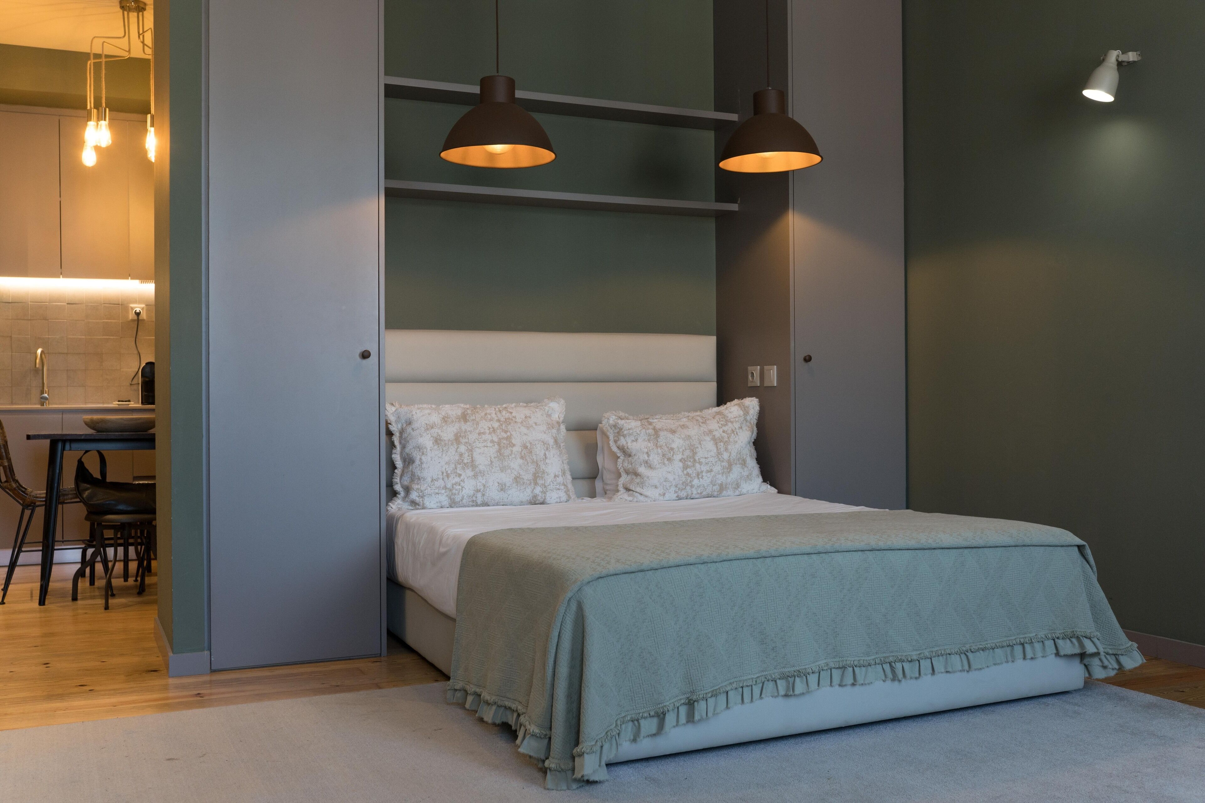 A bedroom with a bed, bedside tables, and a desk with chairs.