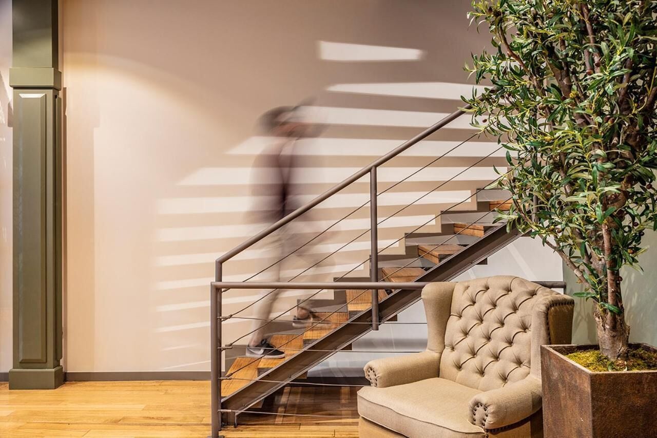 Un intérieur moderne avec un escalier, un fauteuil capitonné et une plante en pot.