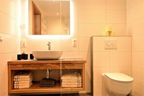 A bathroom with a white sink, wooden vanity, and a toilet. - Residence Martha (Biberwier)
