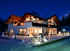 A two-story house with a balcony, a wooden roof, and a snow-covered ground.