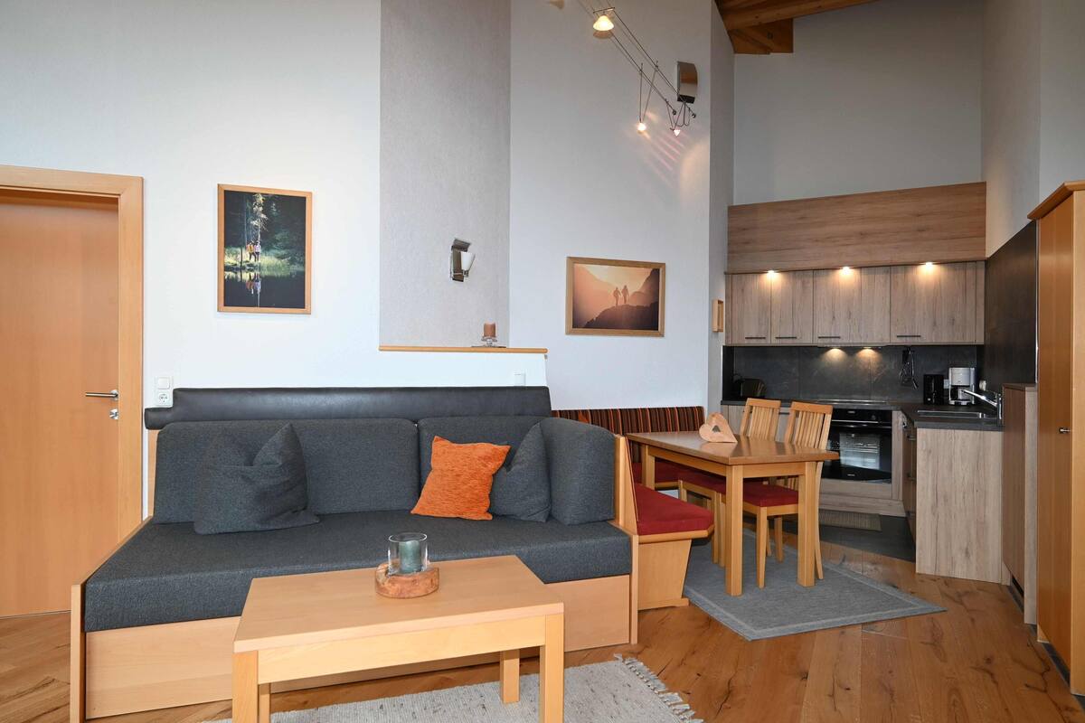 A compact living space with a sofa, a dining table, and a kitchenette.