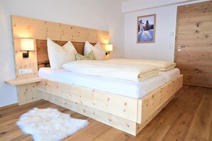 A wooden bed with a headboard, bedside lamps, and a fluffy white rug.