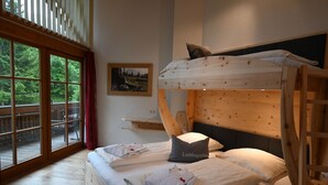 A bunk bed with a headboard, a bedside table, and a window with a view of greenery. - Residence Martha (Biberwier)