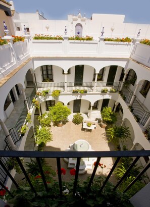 Un patio de varios niveles con paredes blancas, arcos y plantas en macetas.