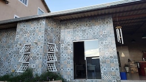 A building with patterned tile walls, a visible window, and a door. - Pousada Aurora (Alto Paraíso de Goiás)