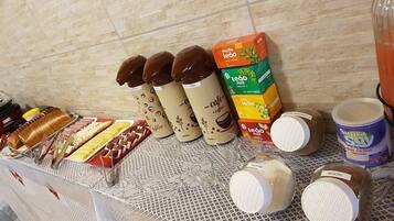 A buffet table with various food items and beverages, including coffee and juice cartons.