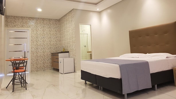 A bedroom with a bed, a desk, a wardrobe, and a shower area. - Pousada Aurora (Alto Paraíso de Goiás)
