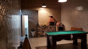 A billiards table in a room with patterned walls, a brick oven, and a potted plant. - Pousada Aurora (Alto Paraíso de Goiás)