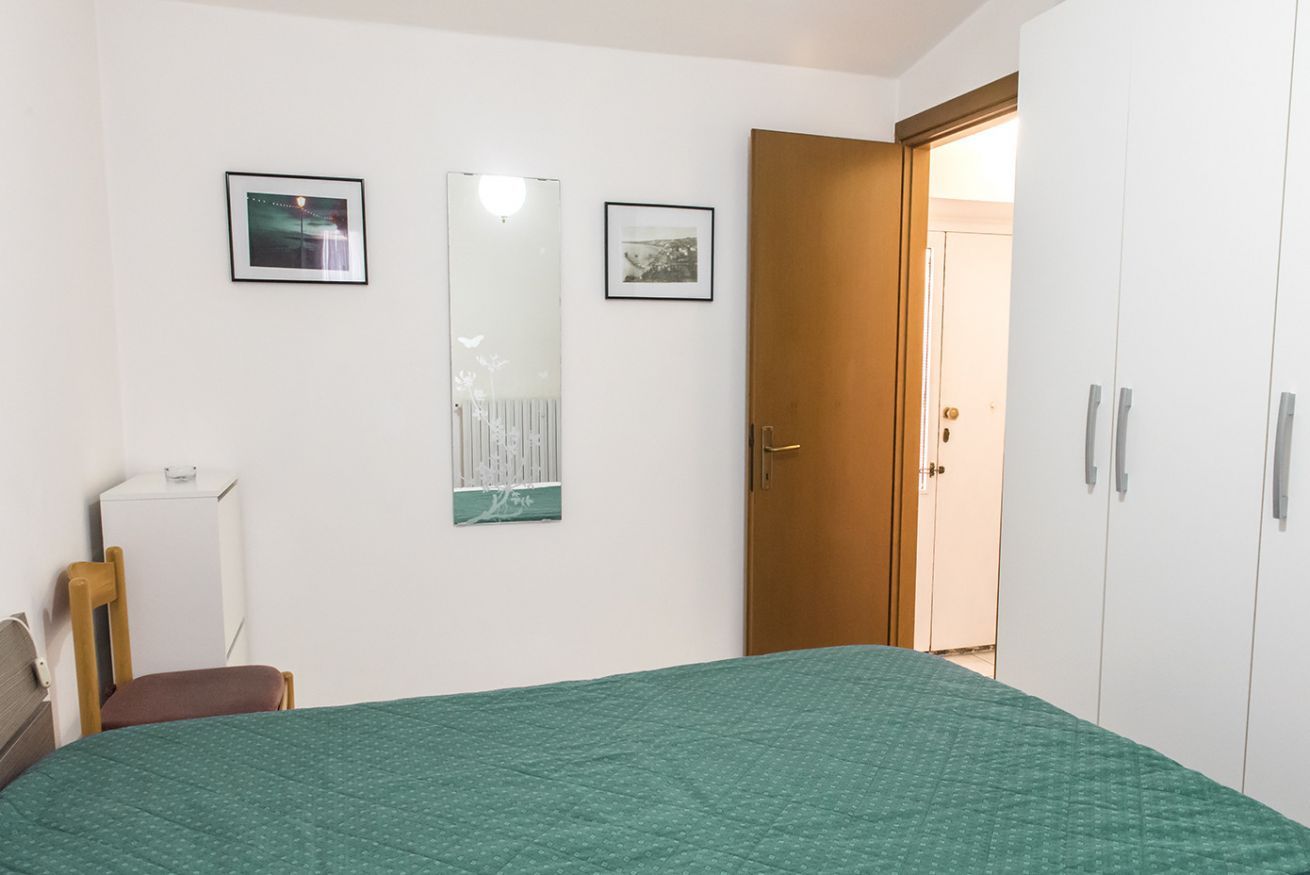 Een slaapkamer met een bed, een kledingkast, een spiegel en twee ingelijste foto's aan de muur.