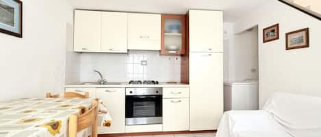 A compact kitchen with a stove, oven, and white cabinets.
