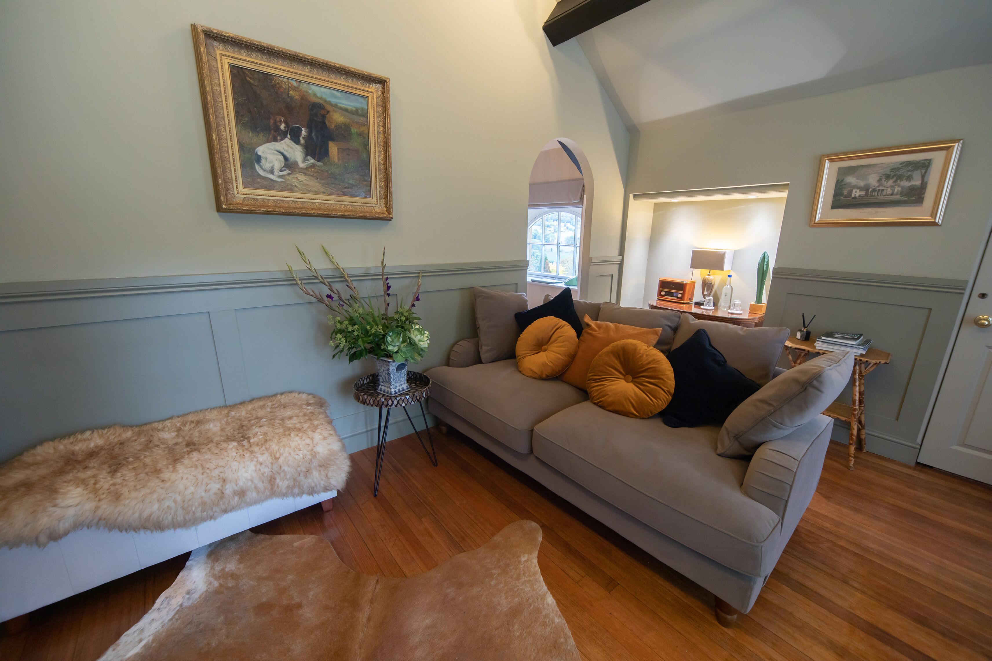 A cozy living room with a sofa, a fur-covered bench, and a painting on the wall.