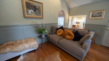 A cozy living room with a sofa, a fur-covered bench, and a painting on the wall.