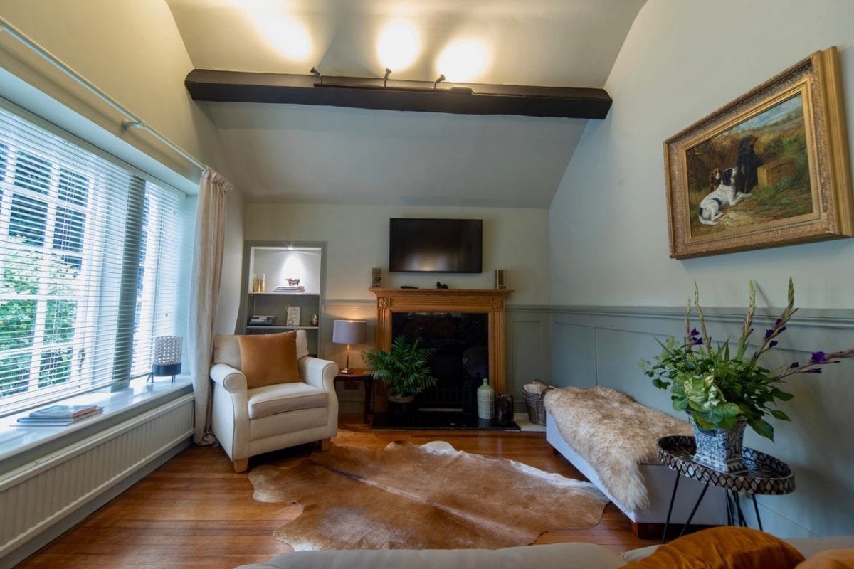 Uma sala de estar acolhedora com lareira, sofá, mesa de centro e televisão na parede.