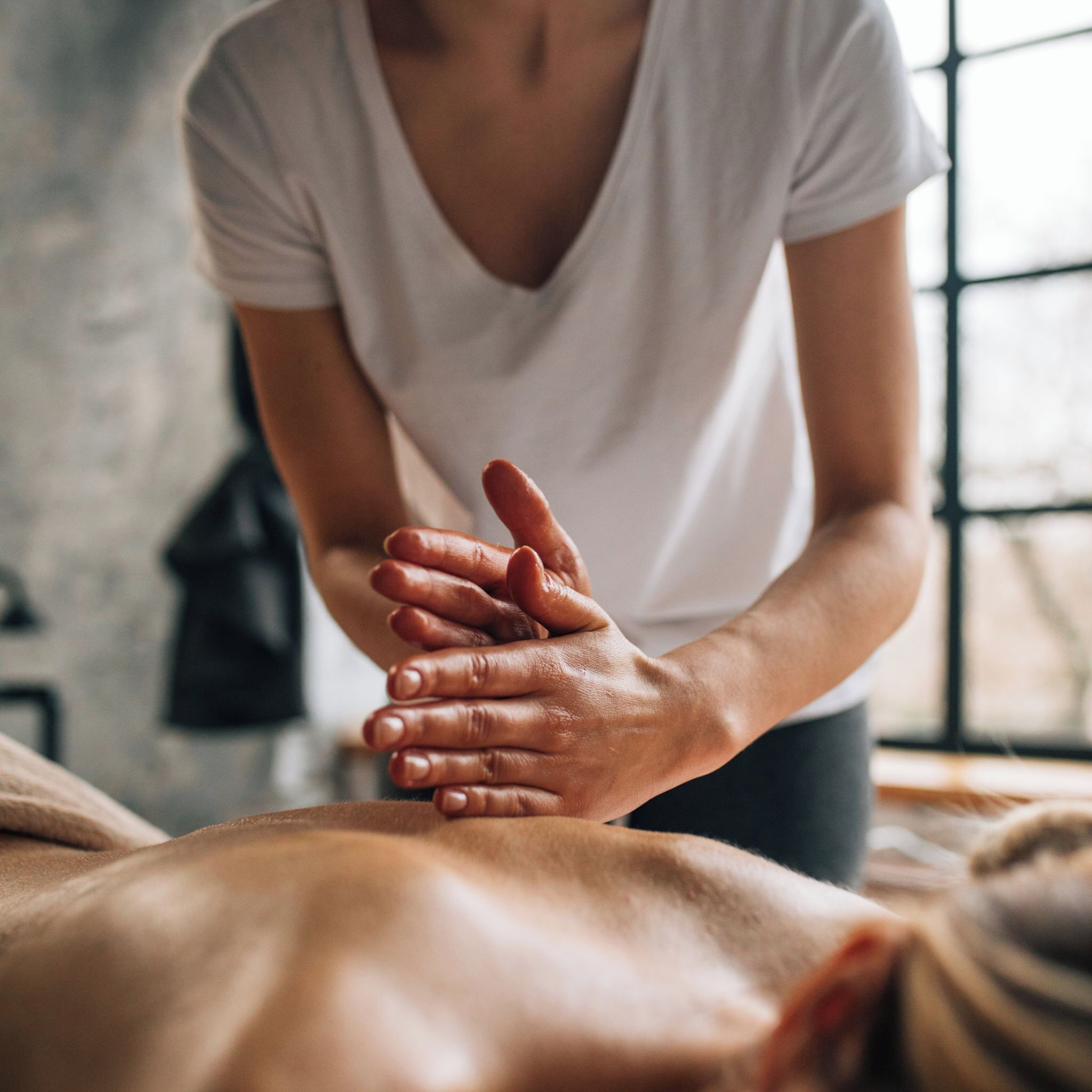 A person attending to another's hands, suggesting a massage or therapeutic session.
