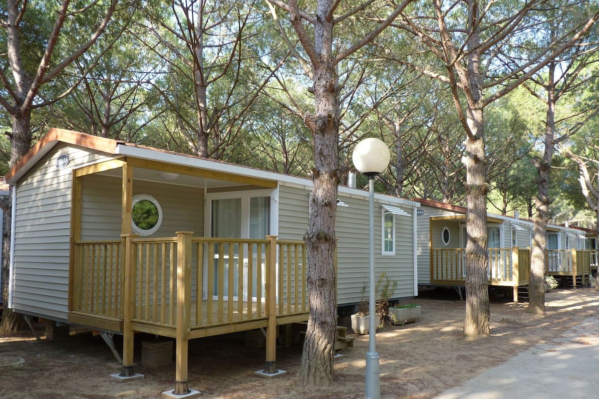 Une rangée de maisons mobiles dotées de terrasses en bois et reliées par une allée centrale.