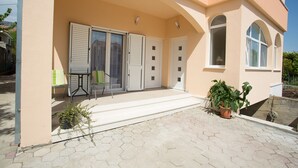 A building with a covered entrance, a small table with chairs, and potted plants. - Apartments Kampanel (Kastela)