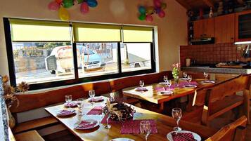 Een restaurant met houten tafels en banken, een uitzicht op de straat door grote ramen en ballonnen aan de muur.