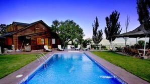 Ein Schwimmbad mit Liegestühlen, eine Holzhütte und Blick auf die Landschaft.