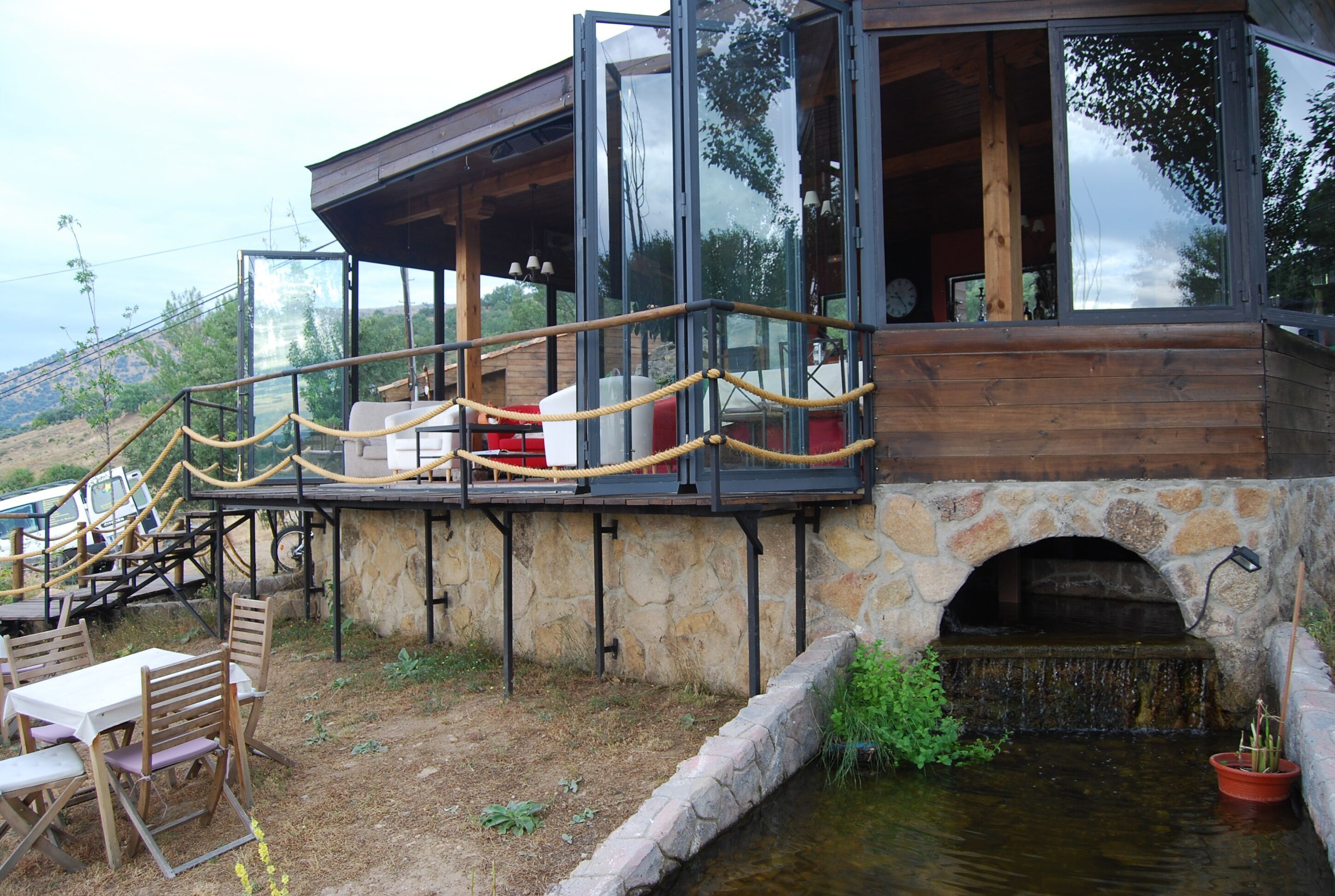 A modern building with a stone archway, wooden deck, and outdoor seating area.