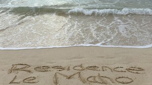 Ein Strand, auf dem die Worte "Residence Le Mano" im Sand geschrieben stehen.