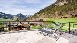 A terrace with exercise equipment overlooking a mountainous landscape with buildings. - Alpine Apartment With Stunning Views (Chateau-d'Oex)