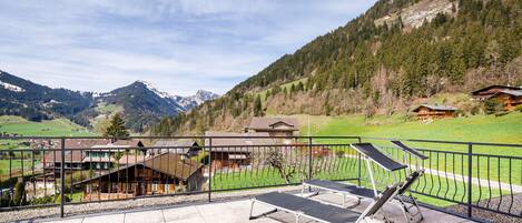 A terrace with exercise equipment overlooking a mountainous landscape with buildings.