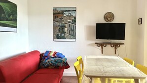 A living room with a red sofa, a table with yellow chairs, a flat-screen TV, and a framed picture on the wall. - N106 - Numana, villa with garden and right sea view (Numana)