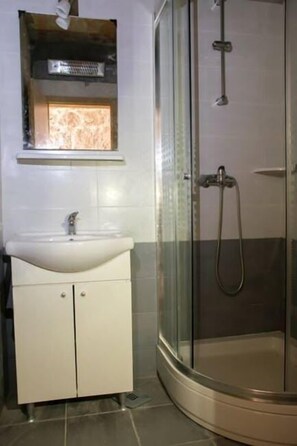 A bathroom with a glass-enclosed shower, a white sink, and a small window above the sink.