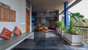 Un balcon avec un coin salon, une télévision et des plantes en pot.