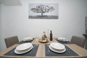 A dining table set for two with plates, cutlery, and glasses, a candle, and a bottle of wine. - Apartment Beny (Kastela)
