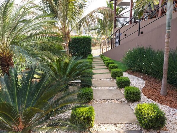 Un camí que condueix a un edifici de disseny modern, envoltat de vegetació cuidada i palmeres.