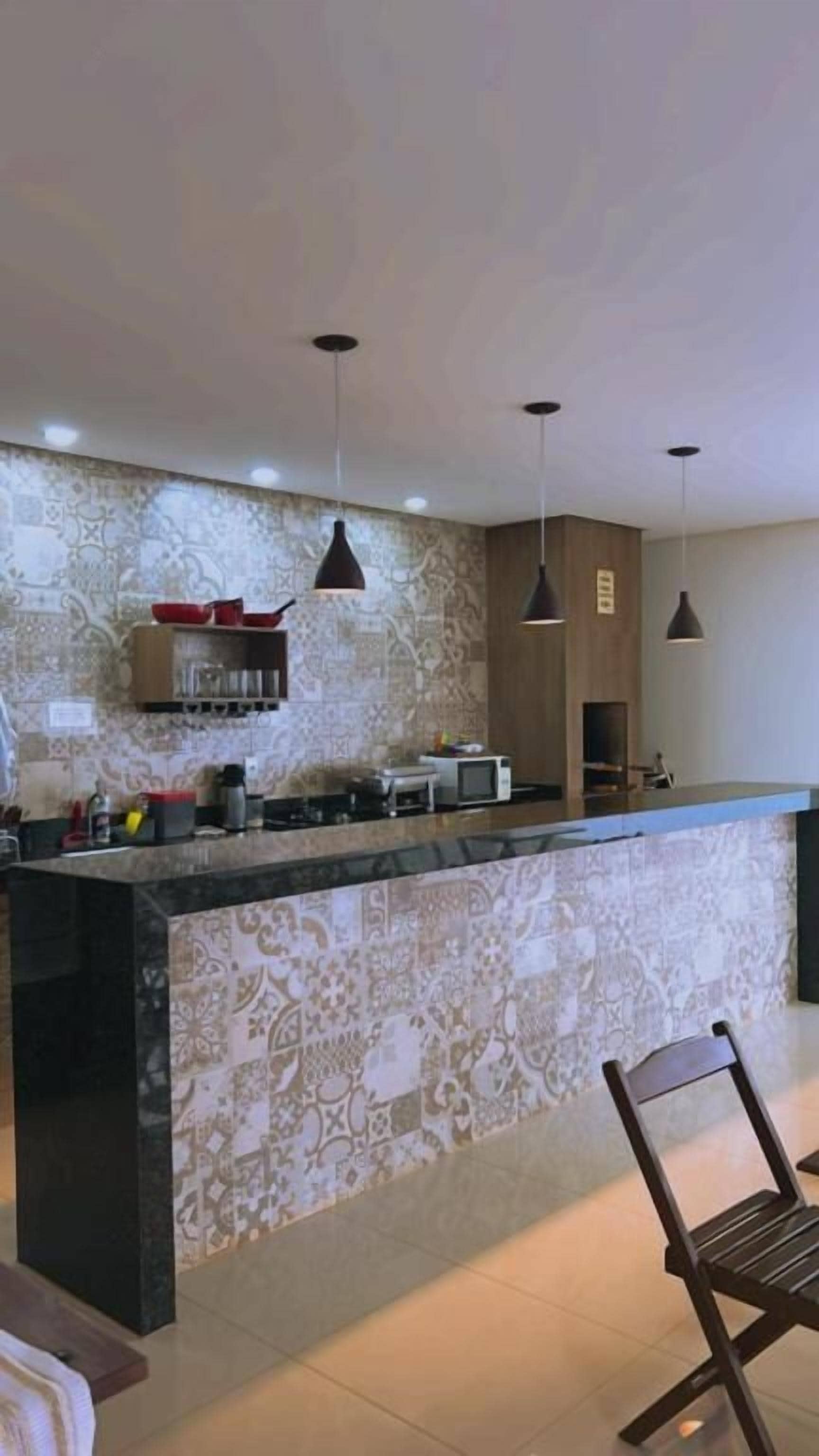 A kitchen with a central island, pendant lighting, and a patterned backsplash.