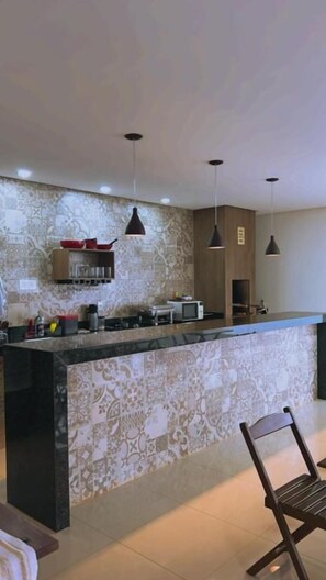 Une cuisine dotée d’un îlot central, de luminaires suspendus et d’un crédence décorée.