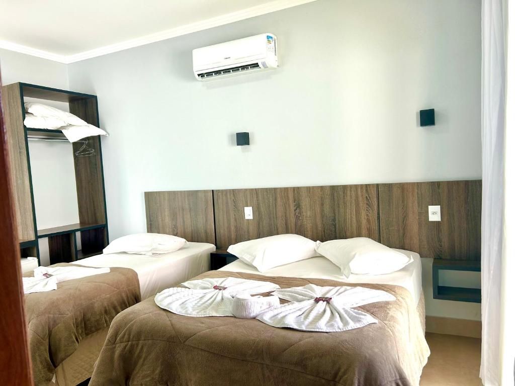 A hotel room with two beds, a wooden headboard, an air conditioning unit, and a mirror.