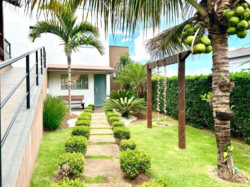 A modern outdoor area with a paved walkway, palm trees, and neatly trimmed bushes.
