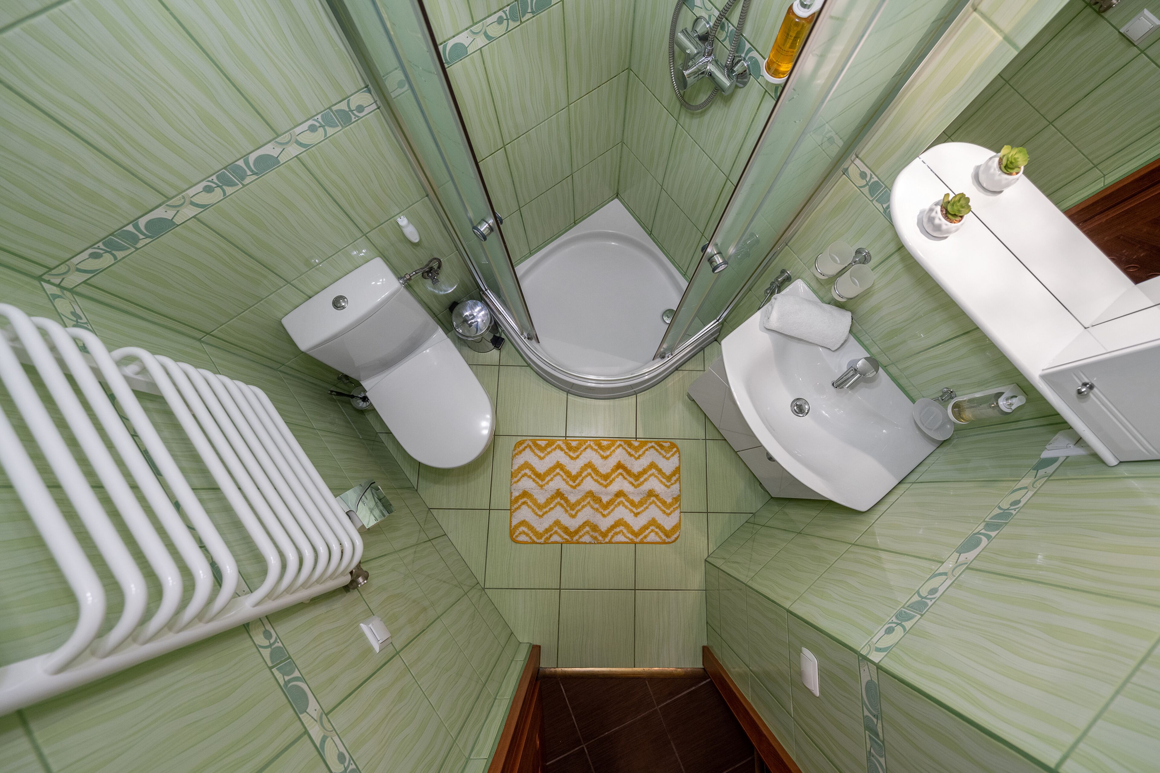 A bathroom with a shower, toilet, sink, and a radiator.