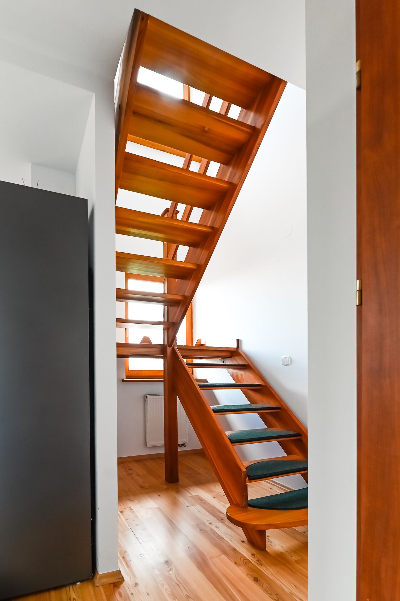 A wooden staircase with a modern design, leading to an upper floor.